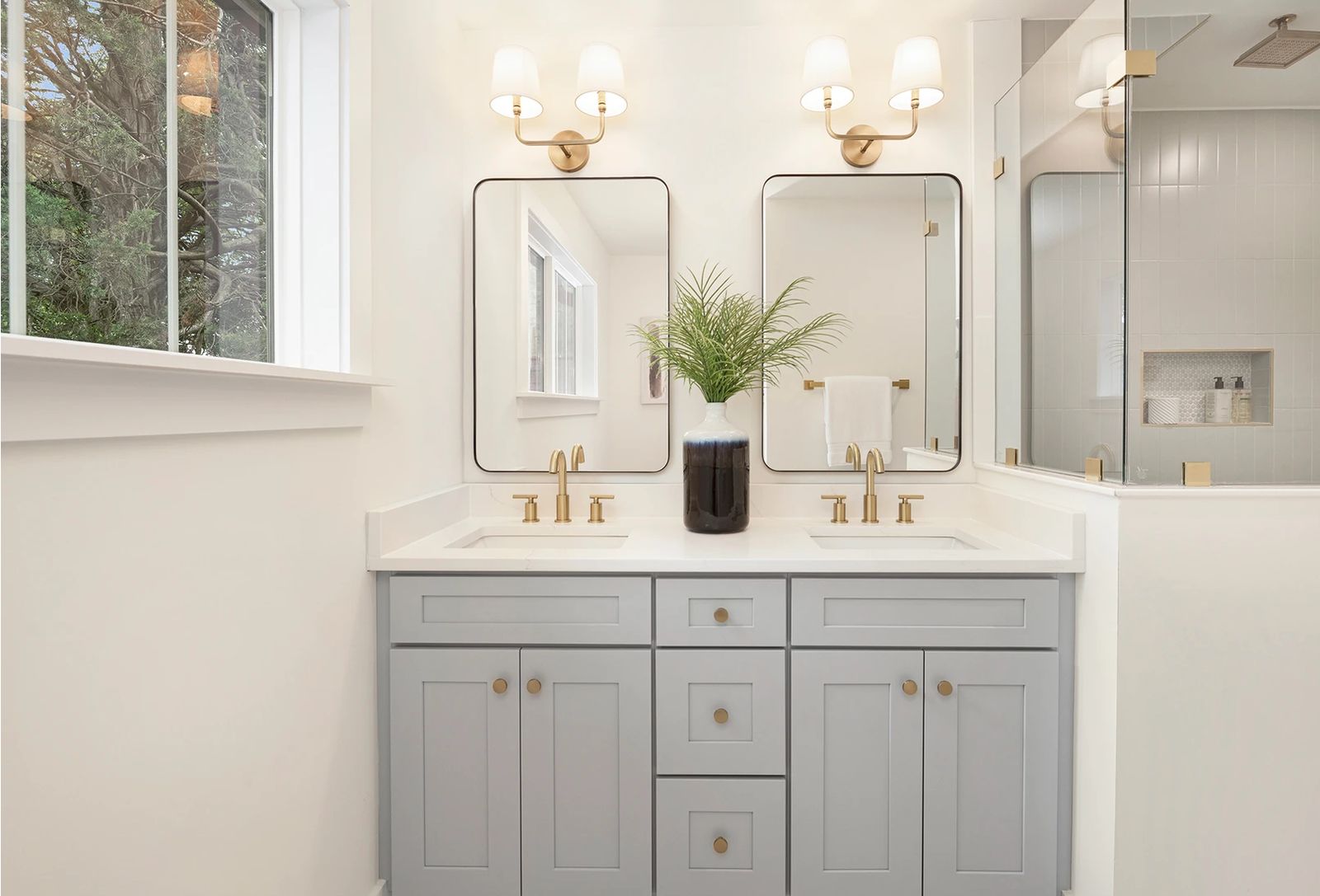 Bathroom with a D6 Dove Grey double vanity, brass faucets and black-framed mirrors