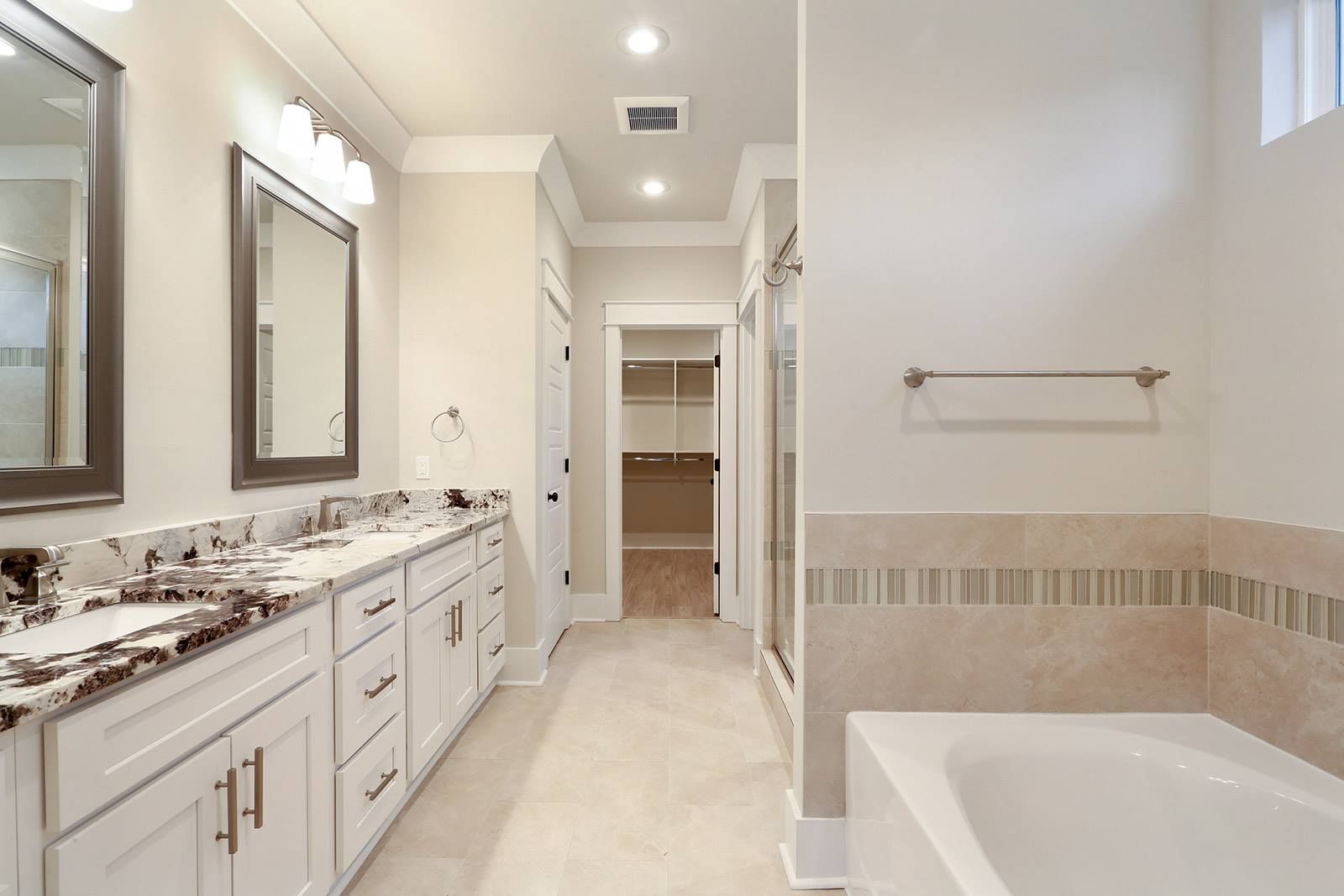 Bathroom with a grey shaker vanity, granite counter and soaking tub
