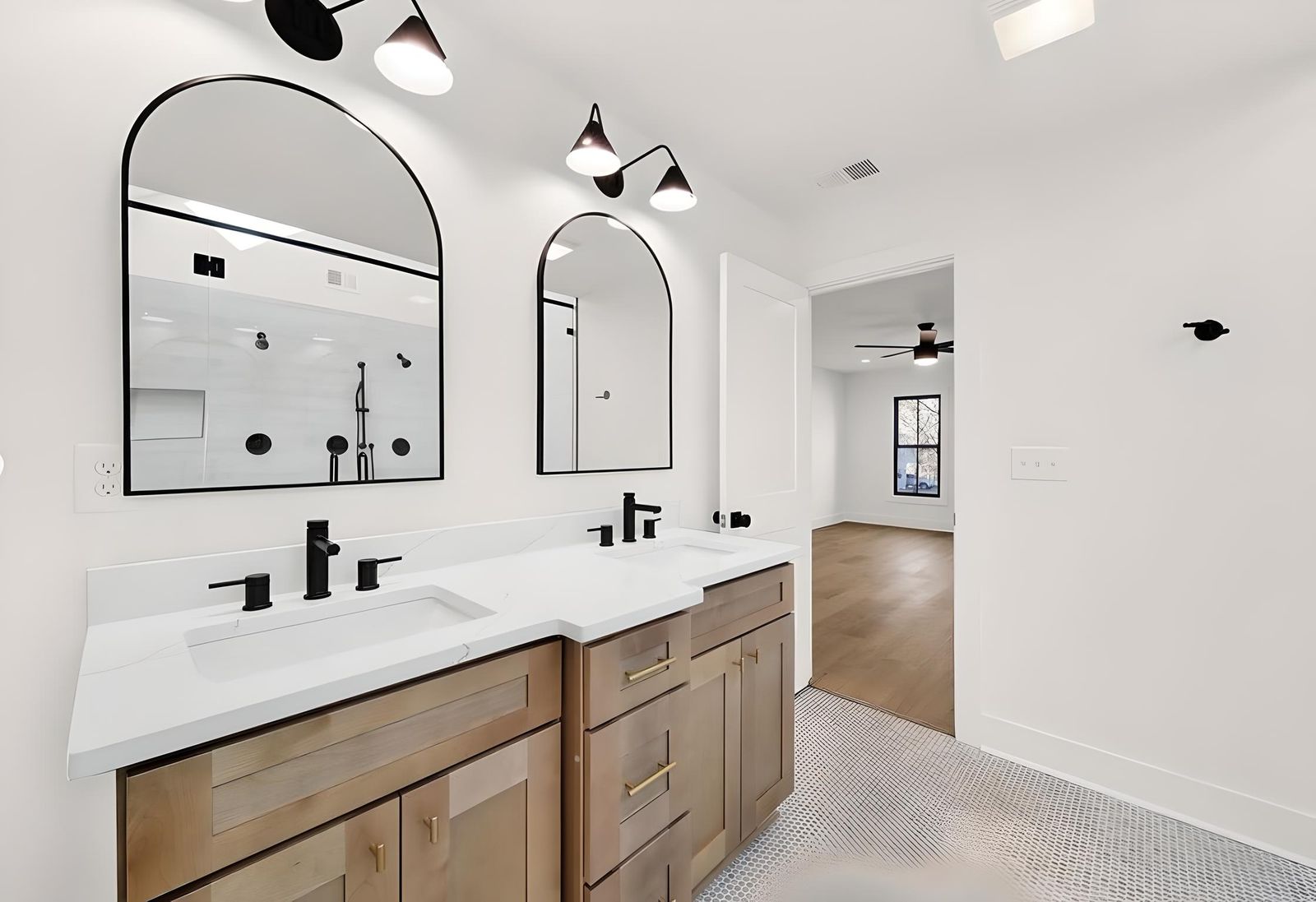 Bathroom with a natural oak double vanity, arched mirrors and black fixtures