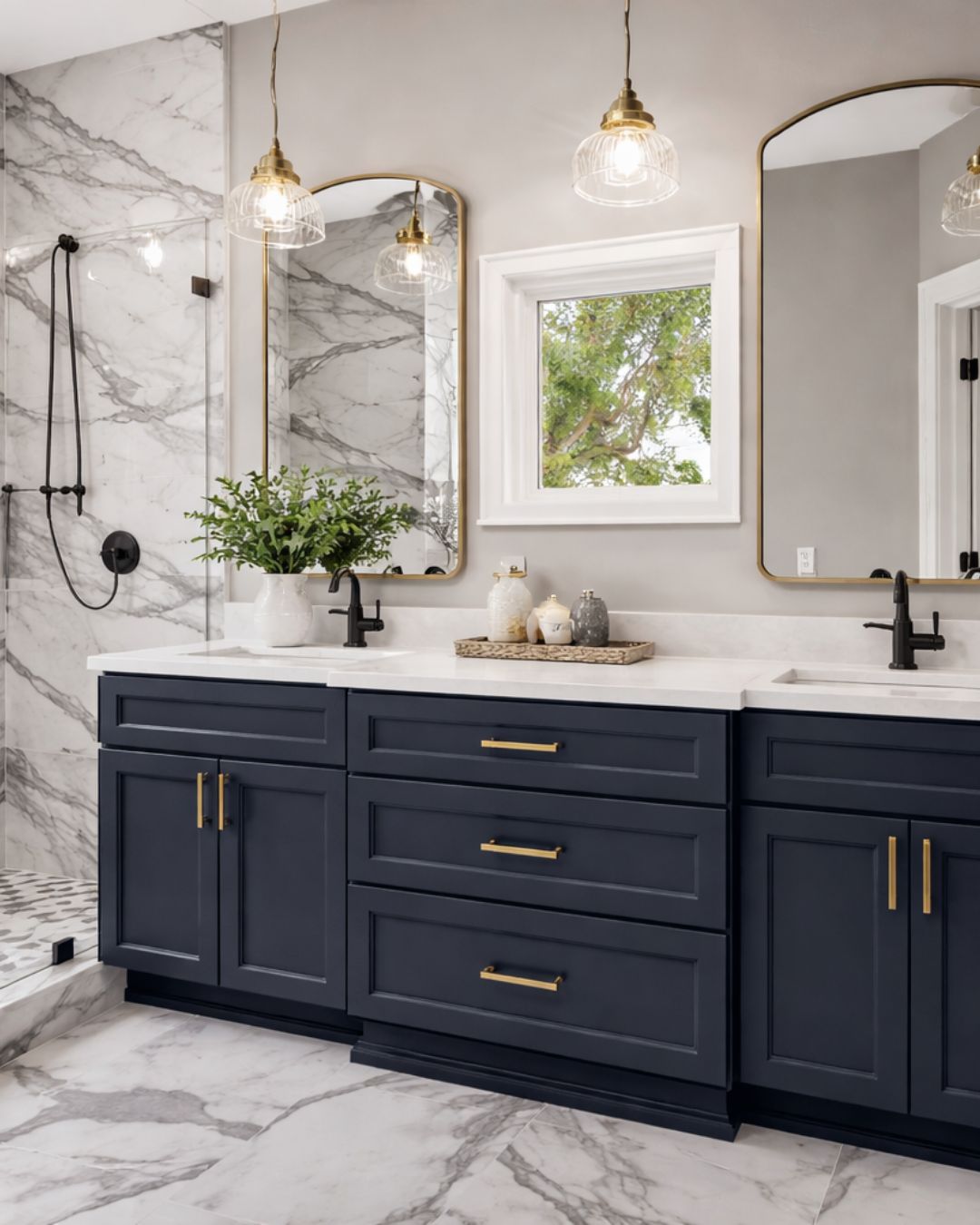 Bathroom vanity in D4 Navy shaker cabinets with brass hardware and marble tile walls