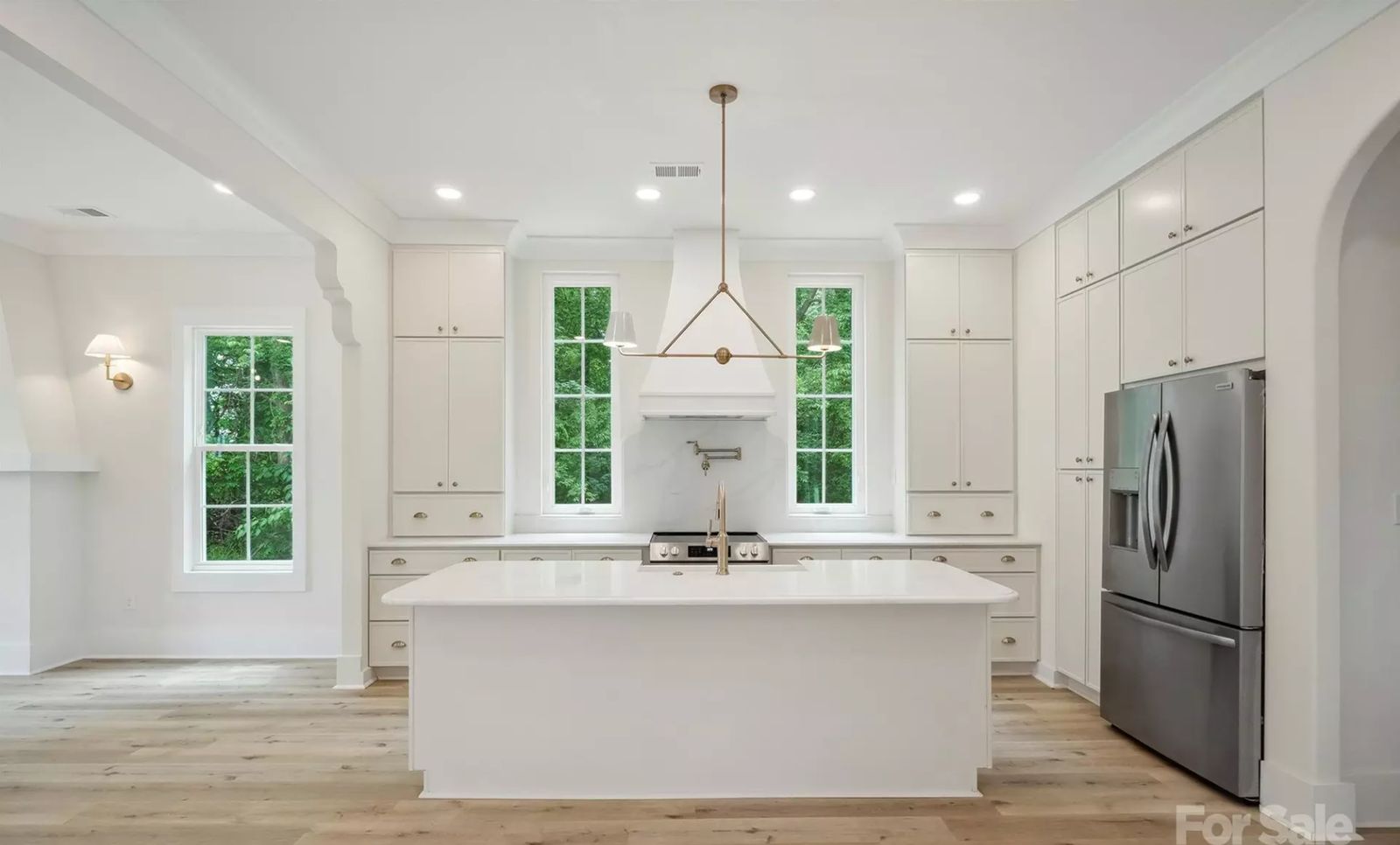 Bright white shaker kitchen with quartz island and arched doorway