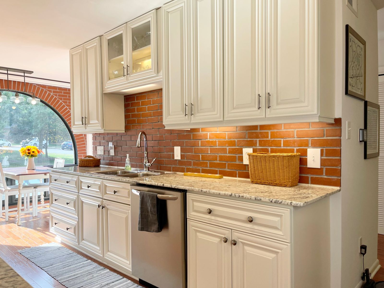 D9 Pearl White raised-panel cabinets with granite counters and brick arch backsplash
