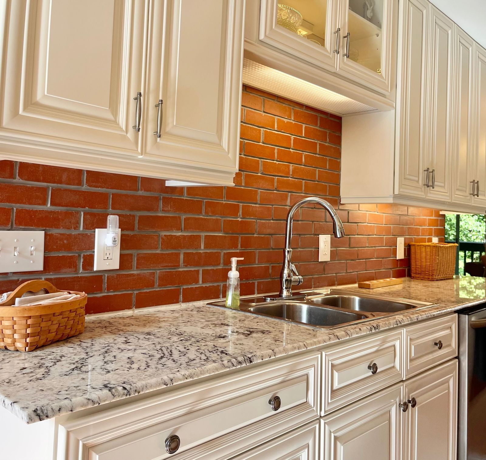 D9 Pearl White raised-panel cabinets with granite counters and exposed brick backsplash