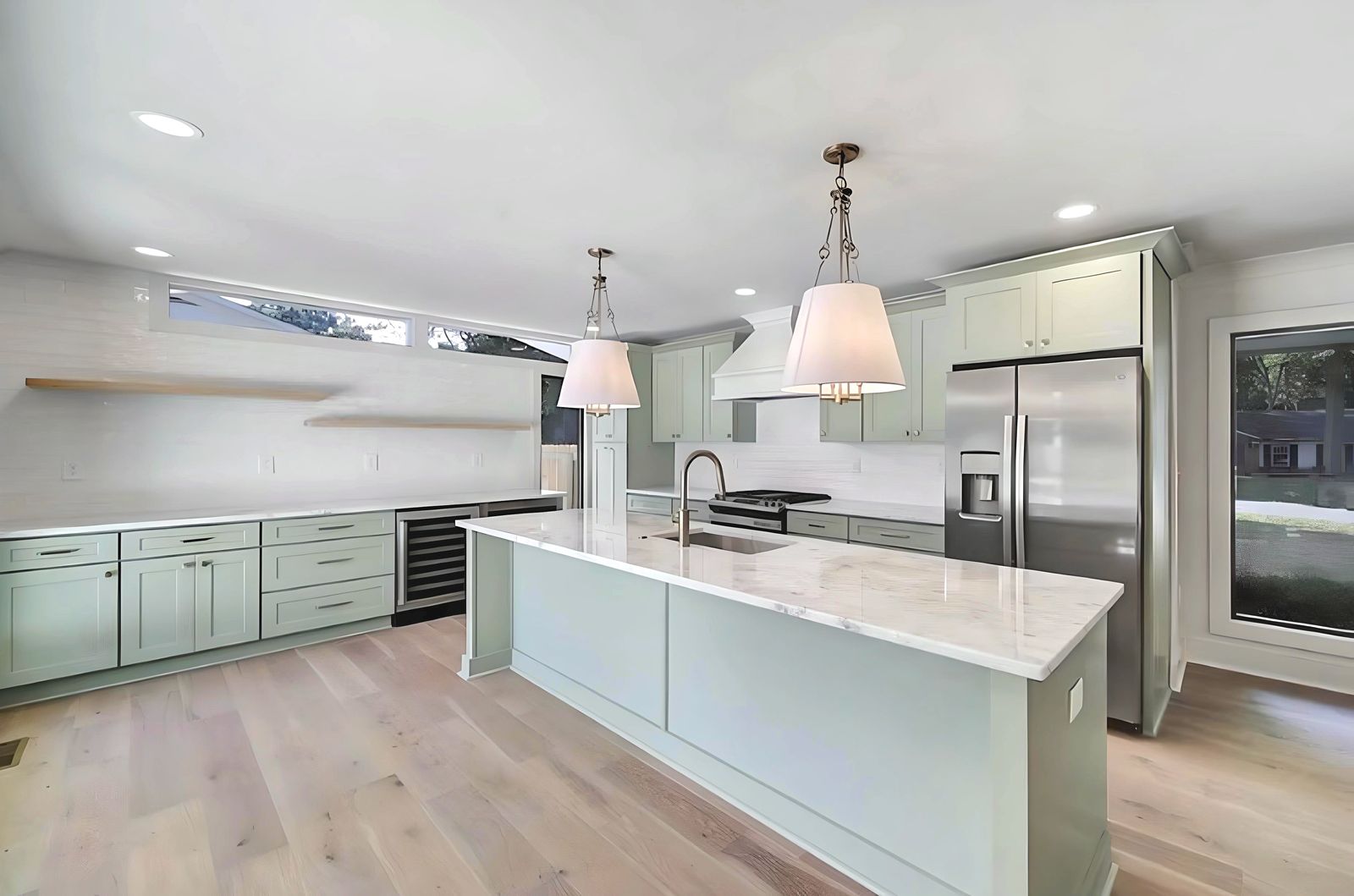 Kitchen with D3 Shallow Green shaker cabinets, long quartz island and white pendants