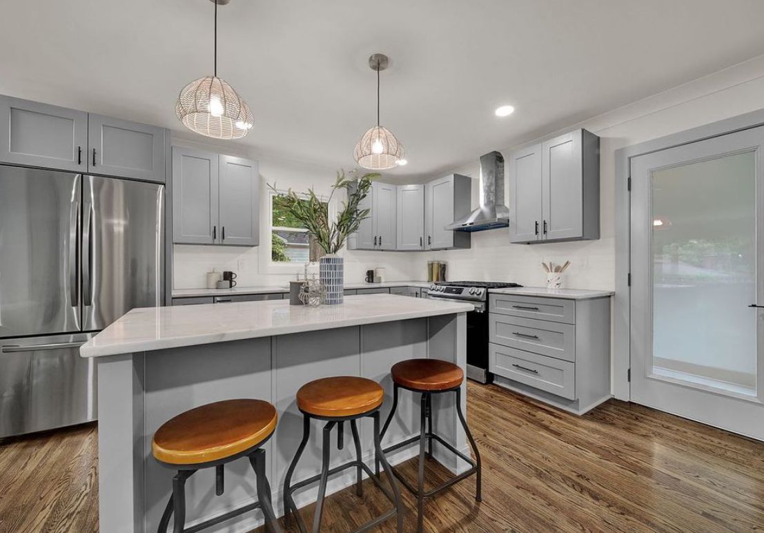 Kitchen with D6 Dove Grey shaker cabinets, white island and leather bar stools