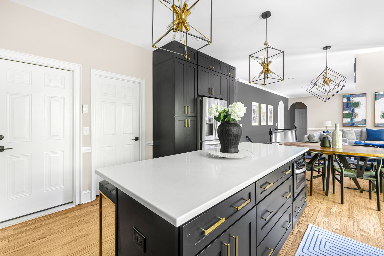 Kitchen with a D8 Black Swan island, black pantry cabinets and gold cage pendants