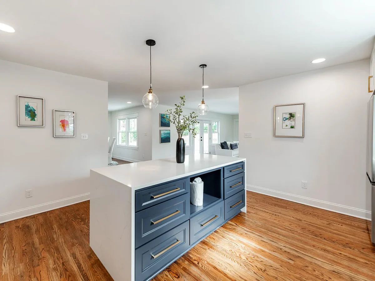 Kitchen with G8 blue-grey shaker island, white perimeter cabinets and glass pendants