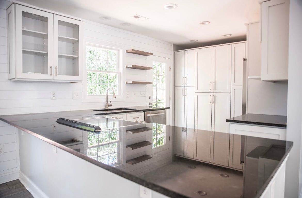 Kitchen with L2 Aveley white shaker cabinets, dark granite counter and floating shelves