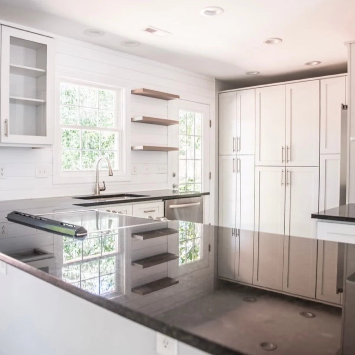 Kitchen with L2 Aveley white shaker cabinets, dark granite counters and floating shelves