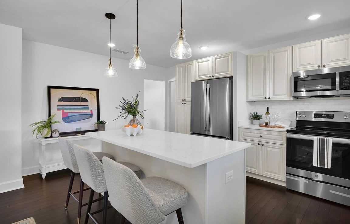 Kitchen with M1 Pure Ivory shaker cabinets, waterfall quartz island and glass pendants
