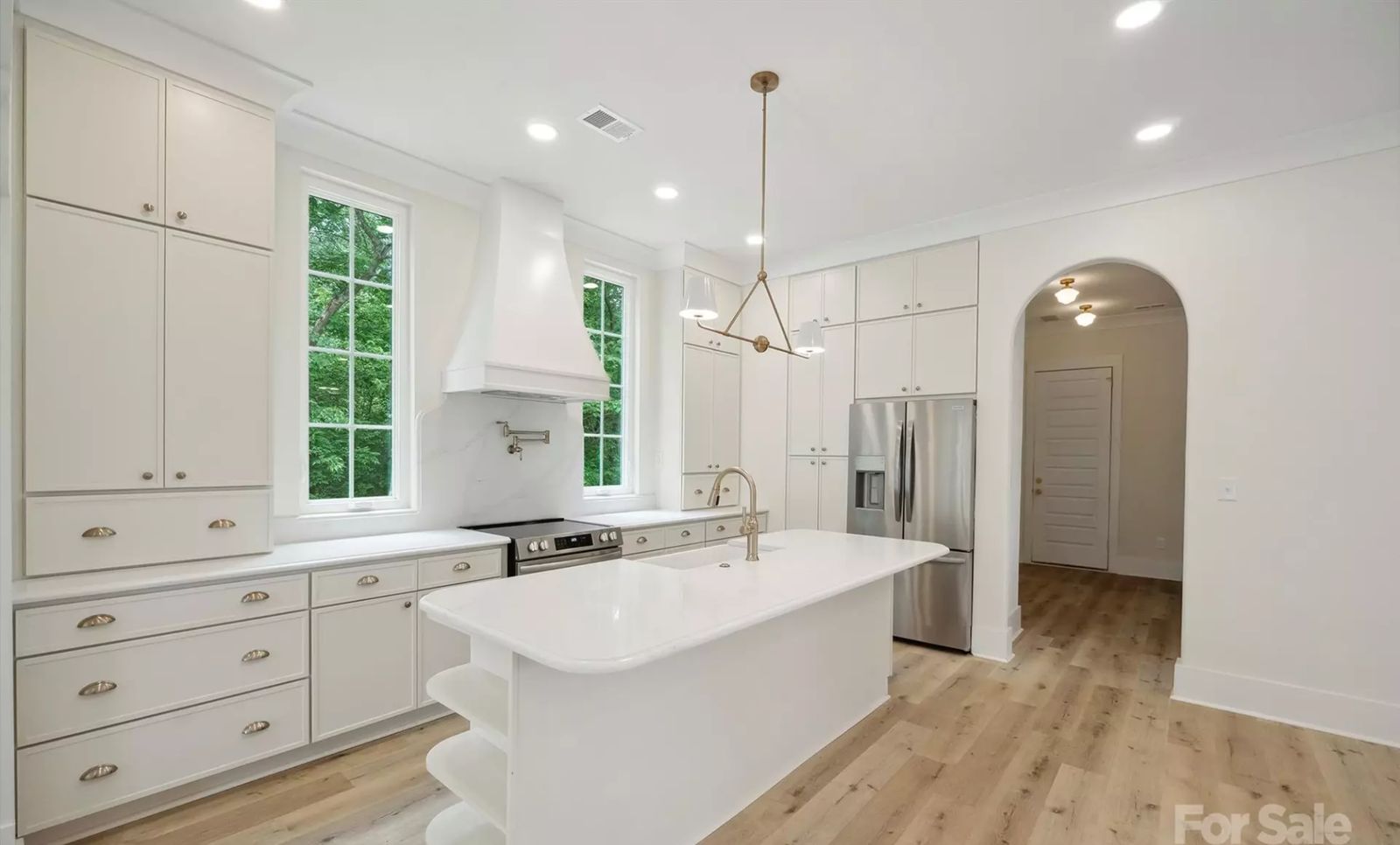 Kitchen with M1 Pure Ivory shaker cabinets, white range hood and arched doorway