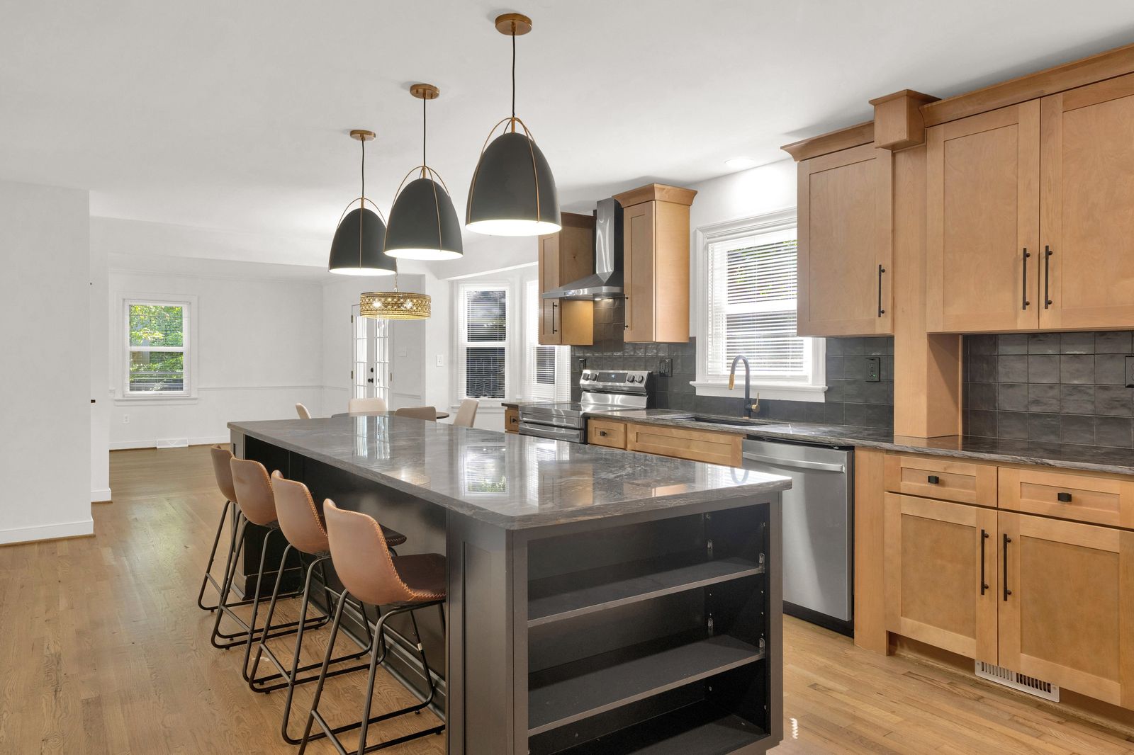 Kitchen with natural wood cabinets, dark grey island and brass pendant lights