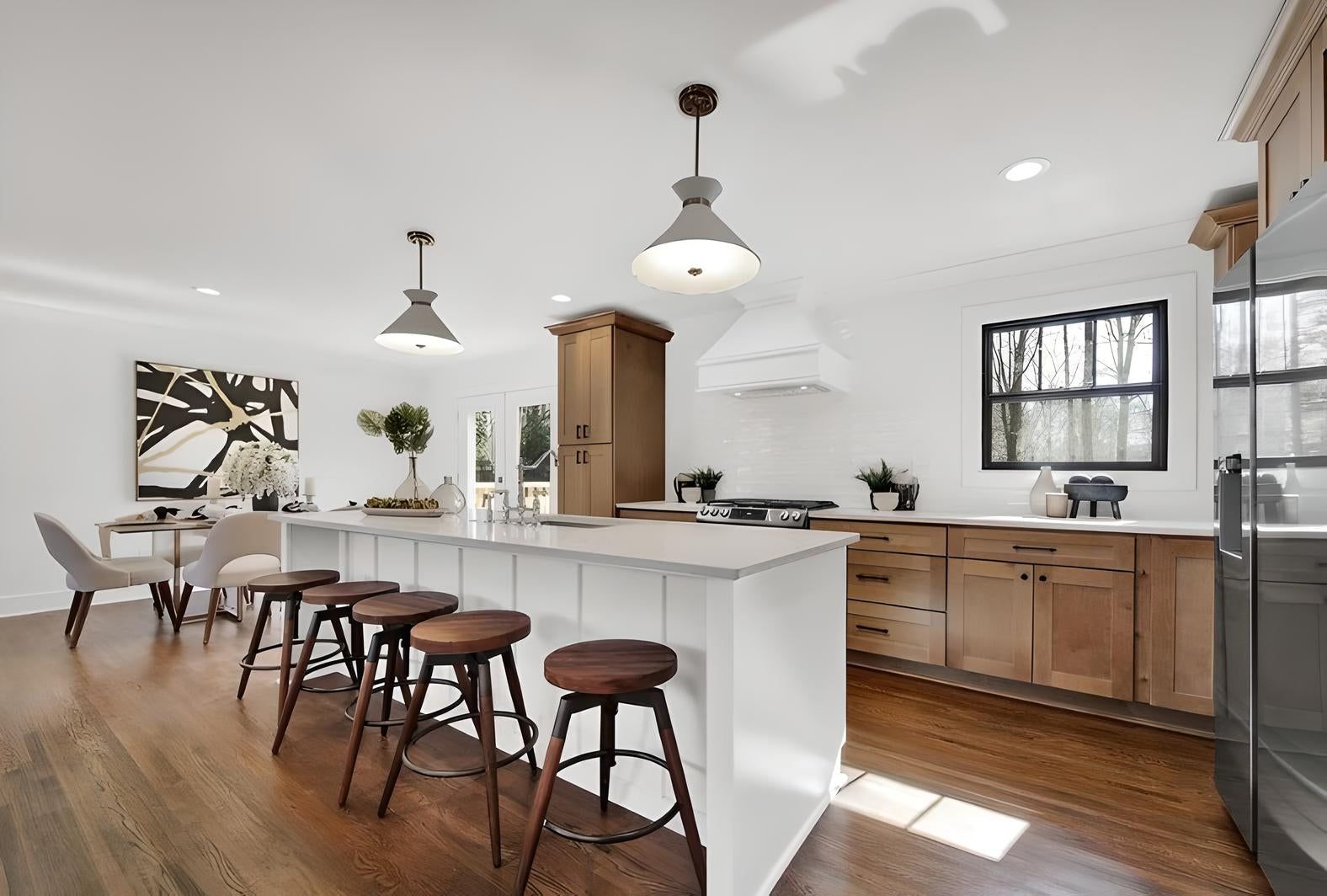 Kitchen with S2 Honey wood cabinets, white island and industrial pendants