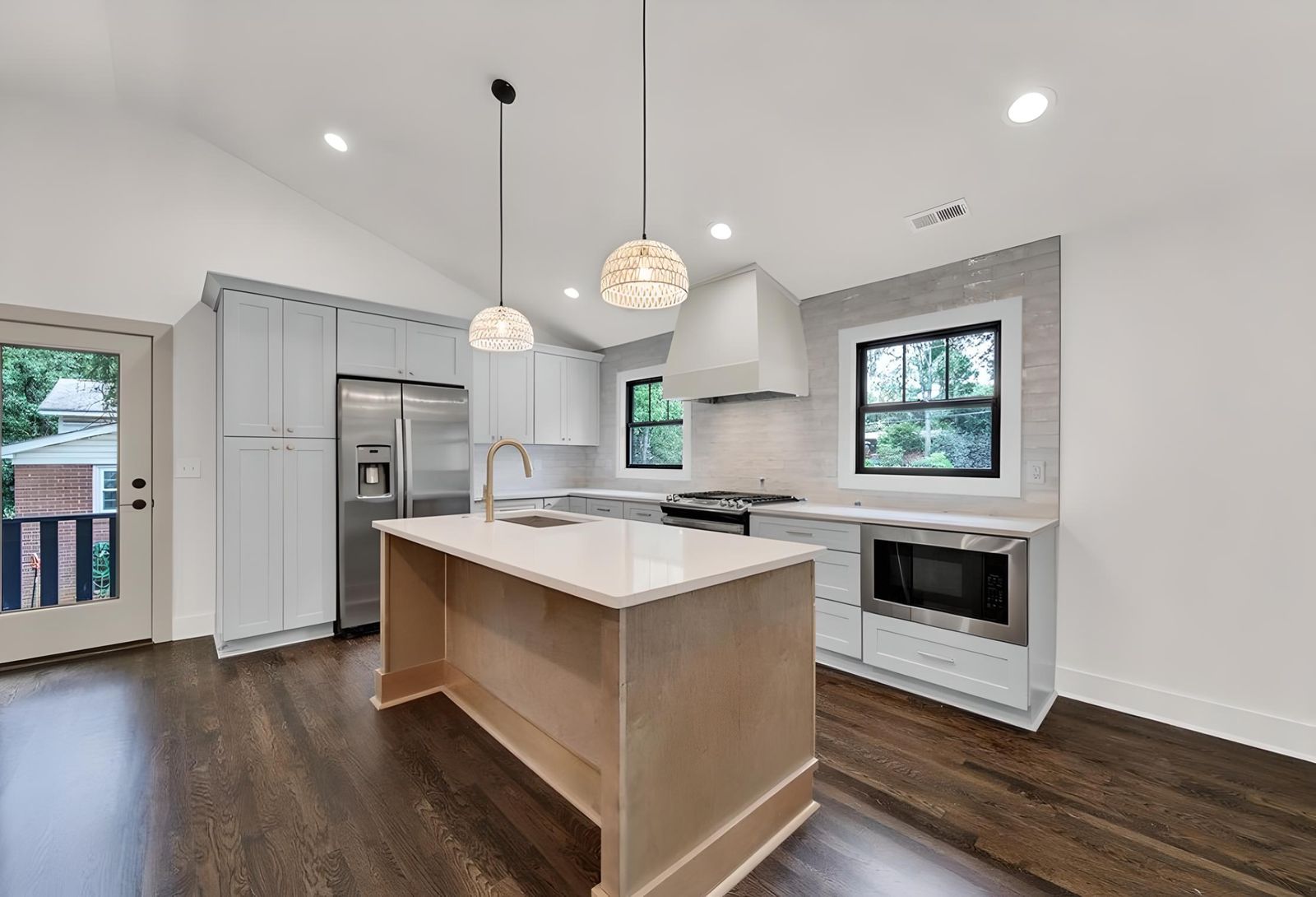 Kitchen with S2 Honey wood cabinets, white island and glass pendants