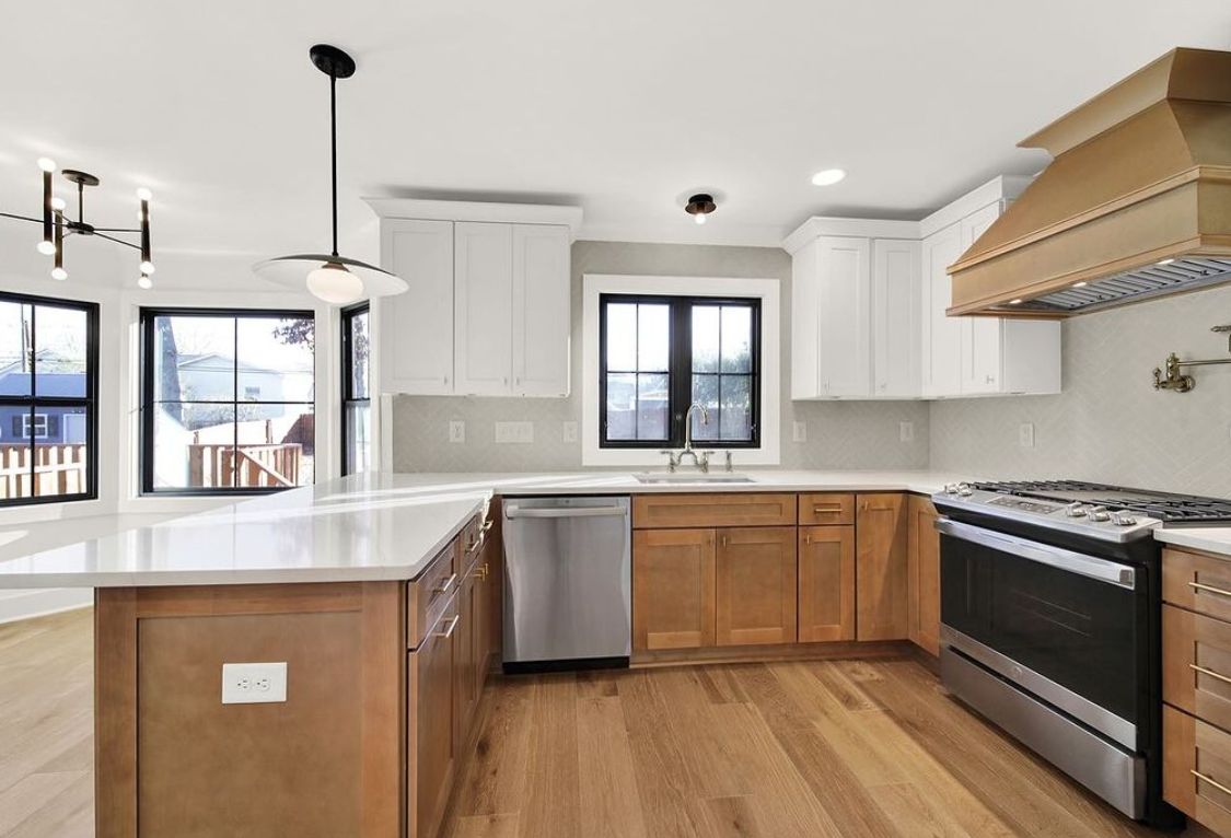 Kitchen with S2 Honey wood cabinets, white uppers, wood range hood and black windows