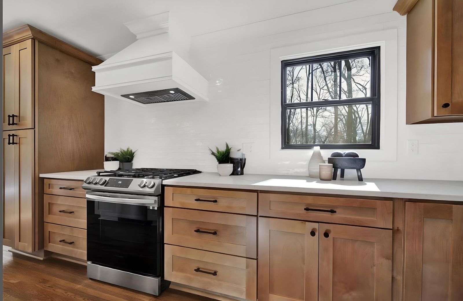 Kitchen with S2 Honey wood shaker cabinets, white range hood and black window