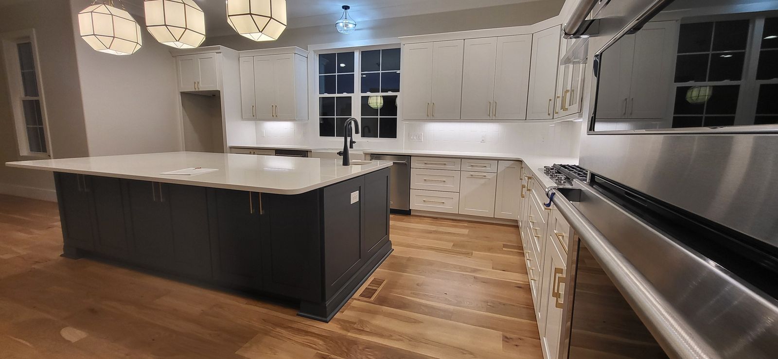 Kitchen with white shaker cabinets, a D5 Cyberspace dark island and stainless appliances
