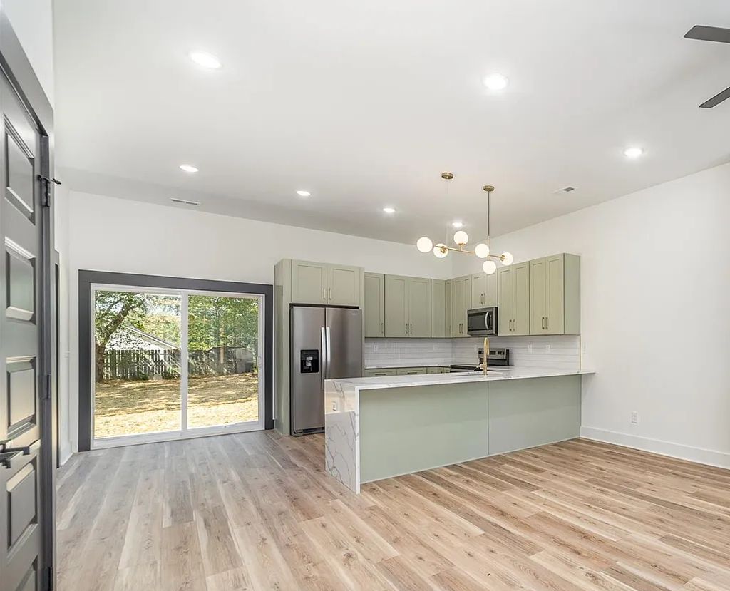 Open kitchen with D3 Shallow Green shaker cabinets and stainless appliances