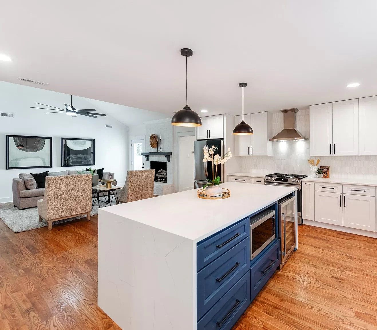 Open kitchen with white shaker cabinets and a D4 Navy island, black pendant lights