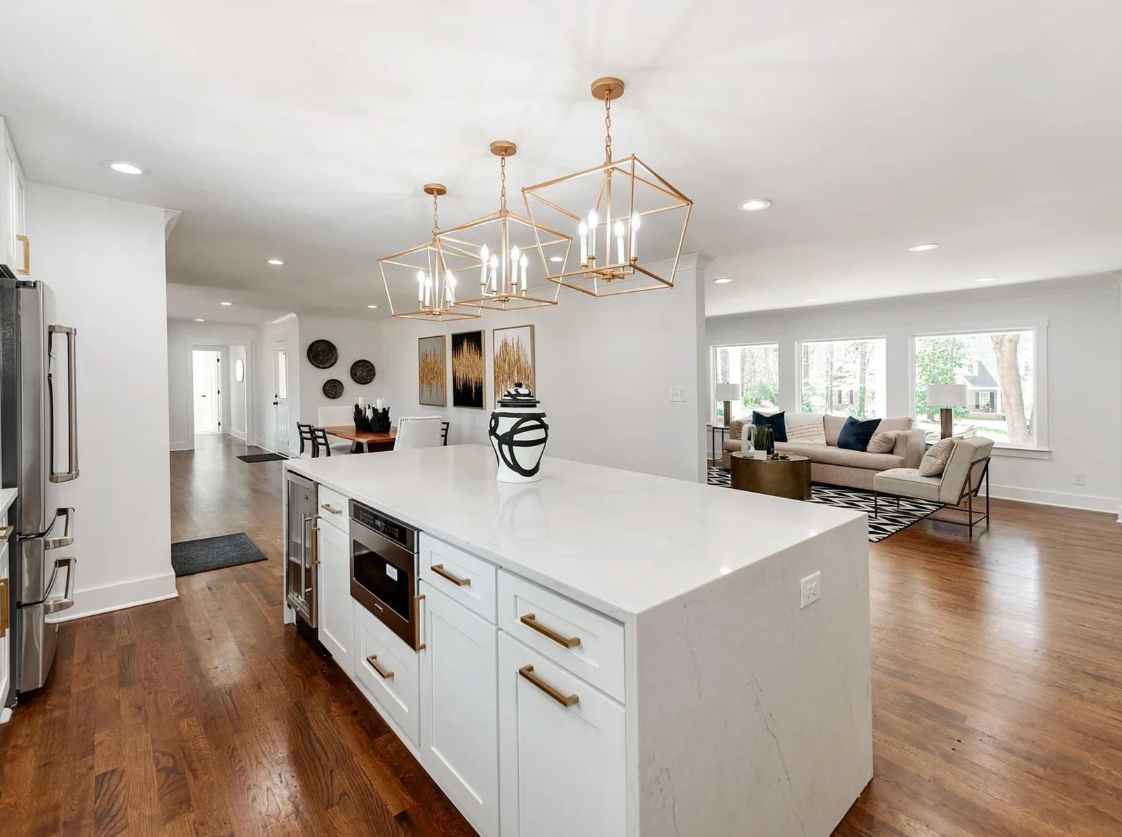 Open white shaker kitchen with quartz waterfall island and brass pendant lighting