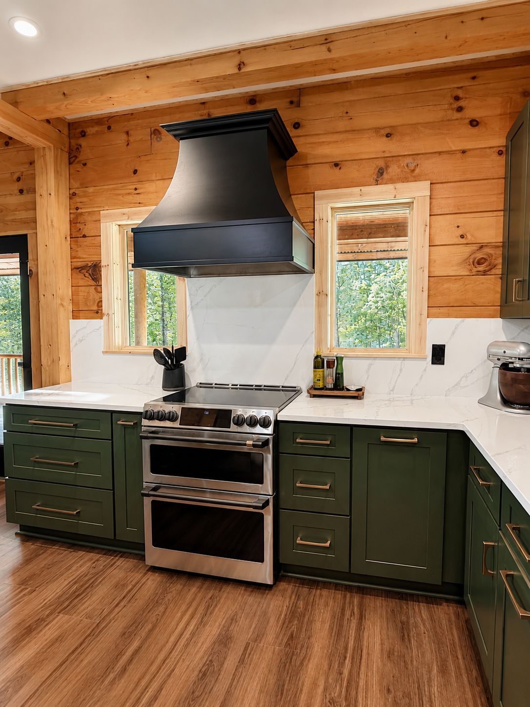 Rustic cabin kitchen with D7 Forest Green shaker cabinets, black range hood and knotty pine walls