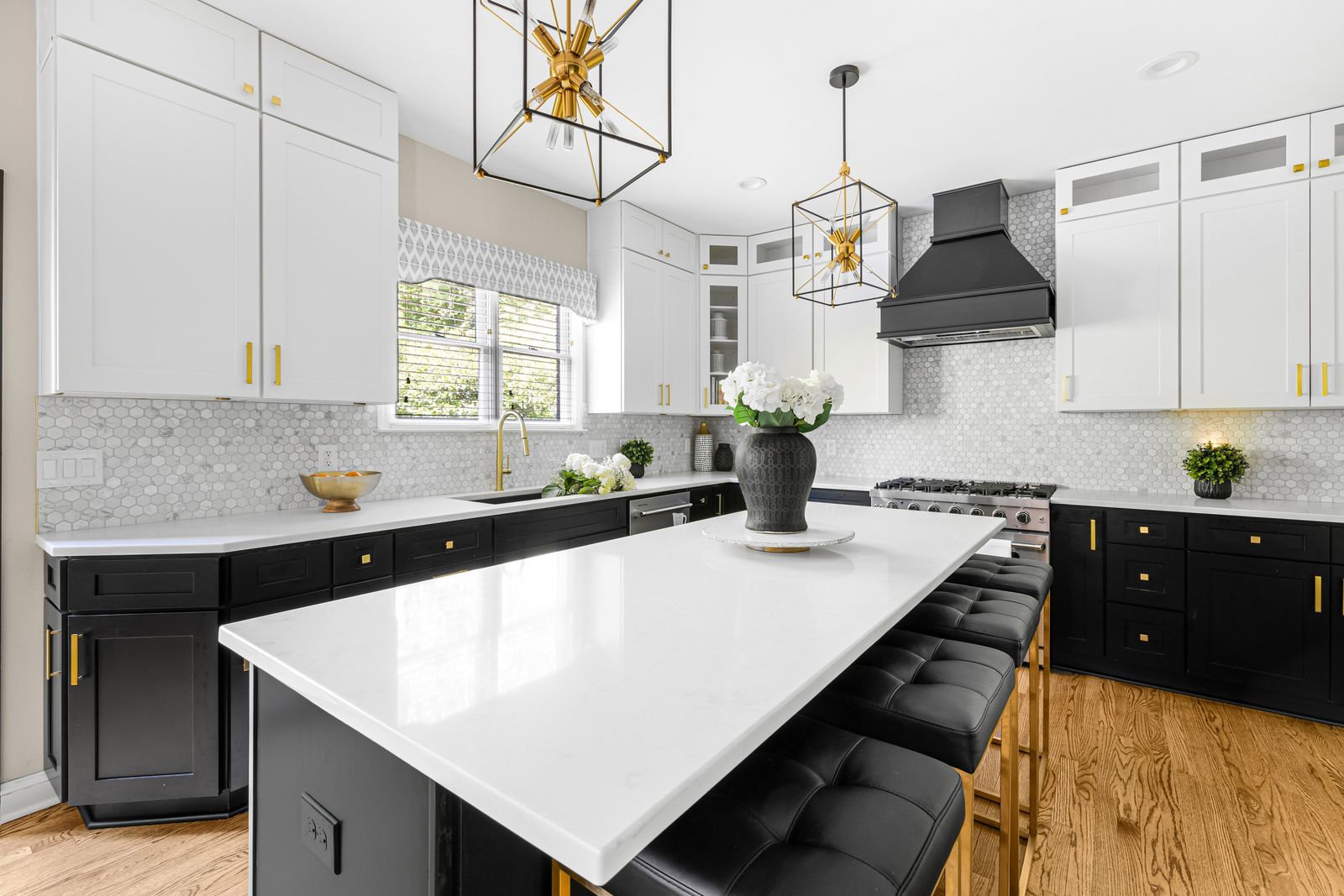 Two-tone kitchen with white uppers and D8 Black Swan base cabinets, quartz island and gold pendants