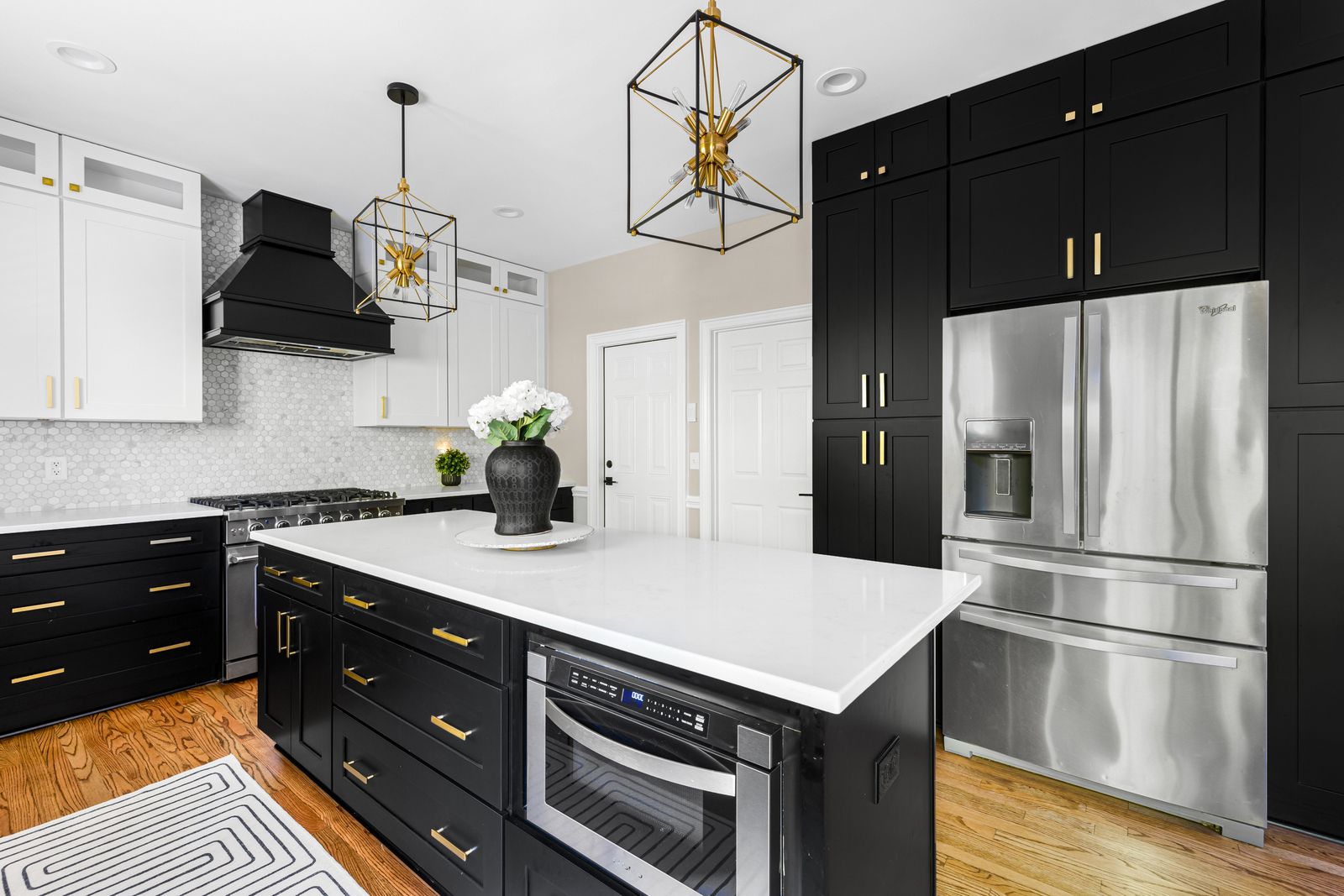 Two-tone kitchen with white uppers and D8 Black Swan base cabinets, gold cage pendant
