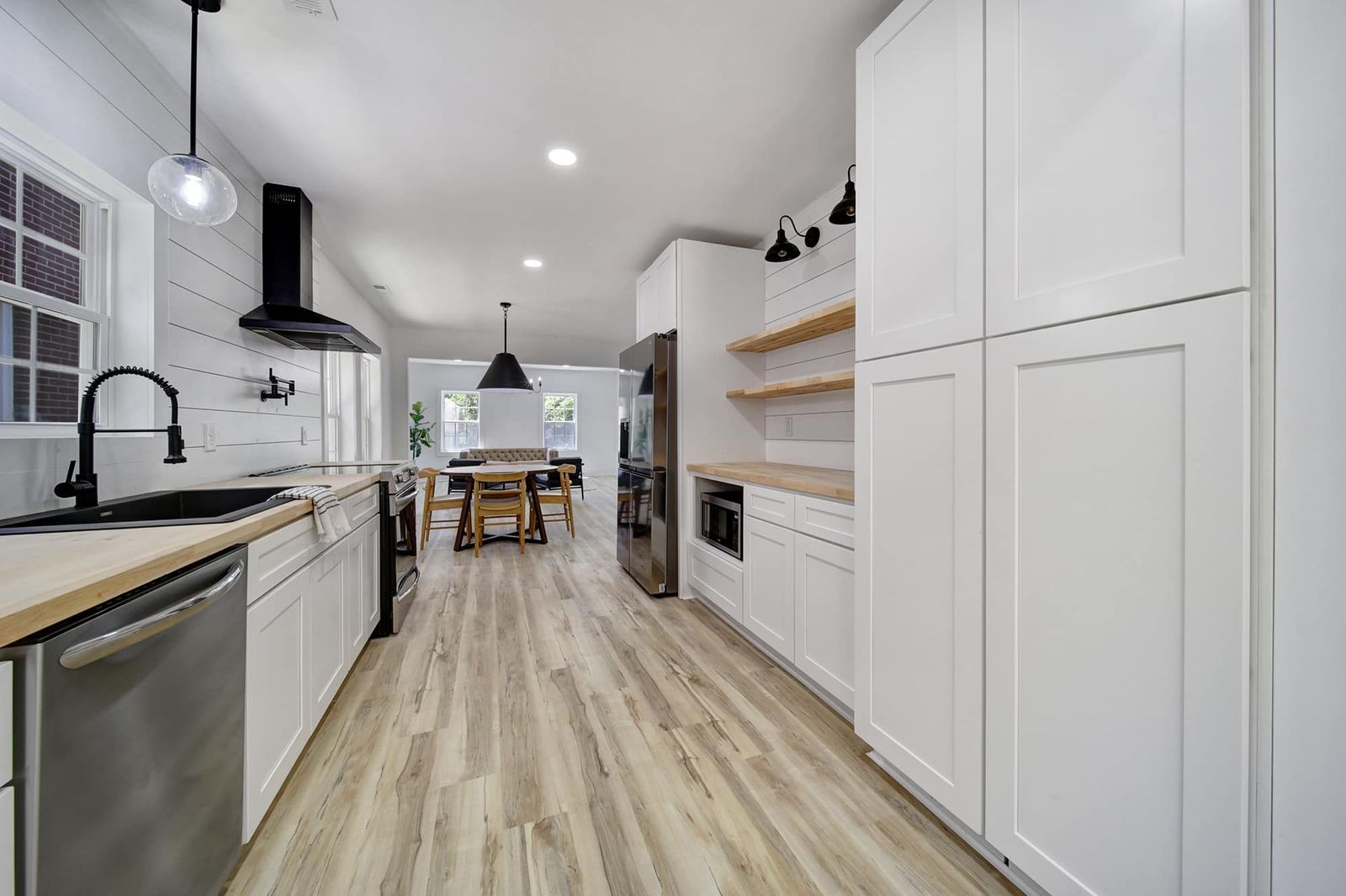 White shaker kitchen with black faucet, stainless dishwasher and tall pantry cabinets