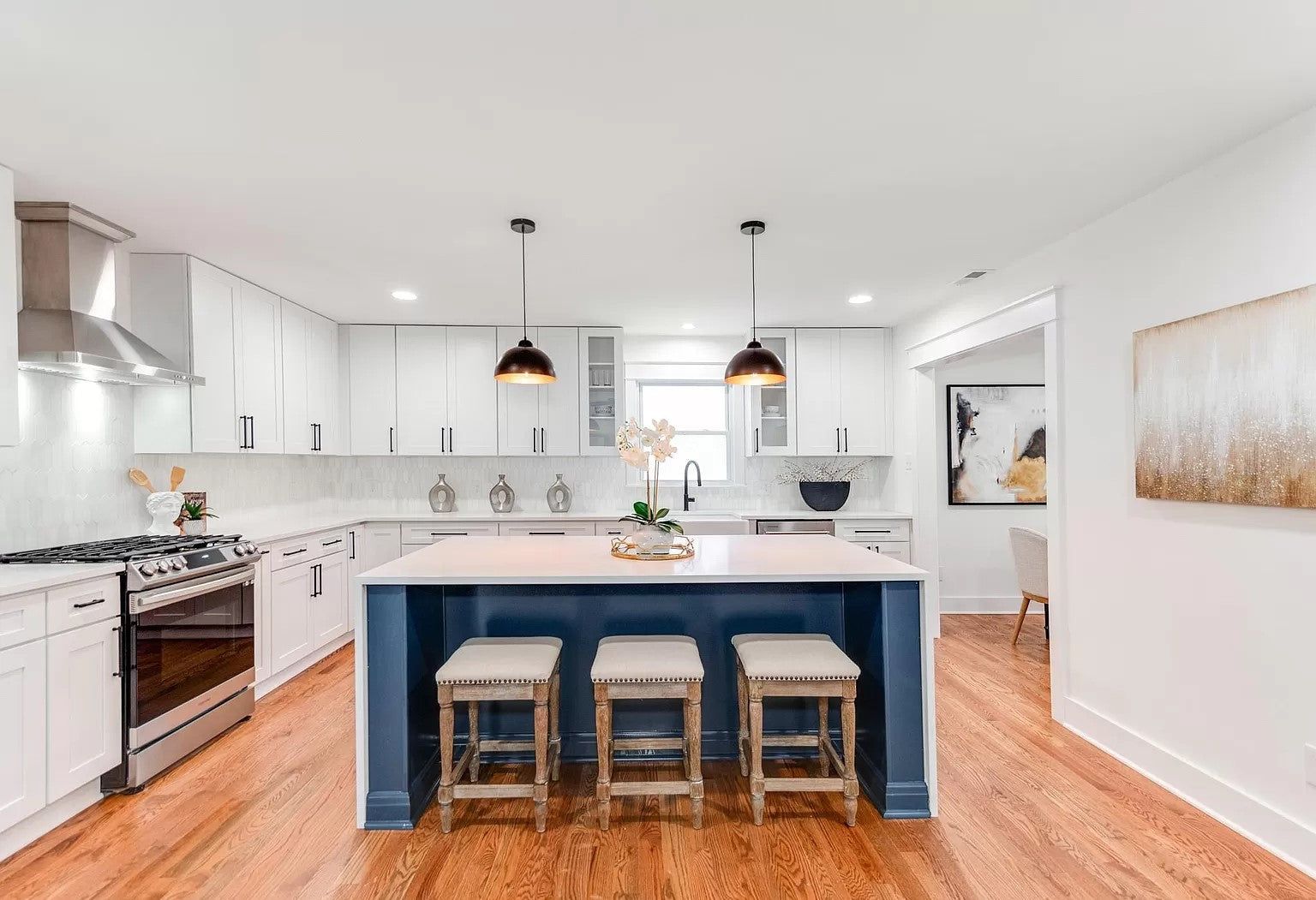 White shaker kitchen with a D4 Navy island, quartz counters and stainless range