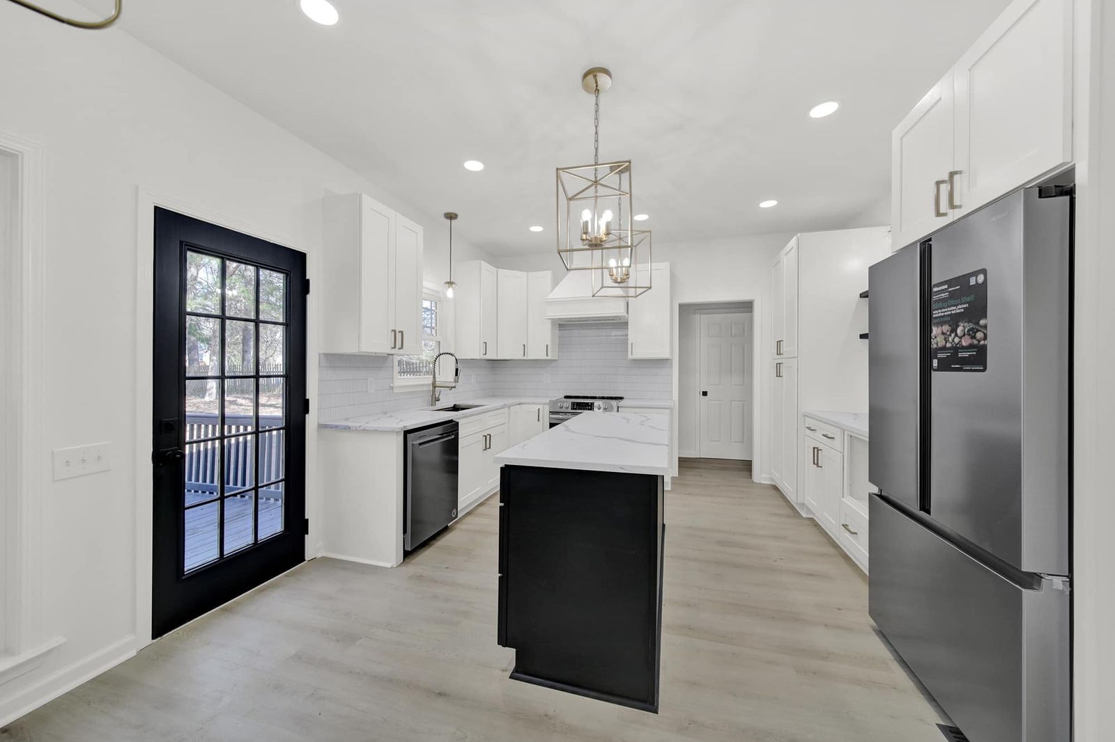 White shaker kitchen with a D8 Black Swan island, black door and stainless refrigerator