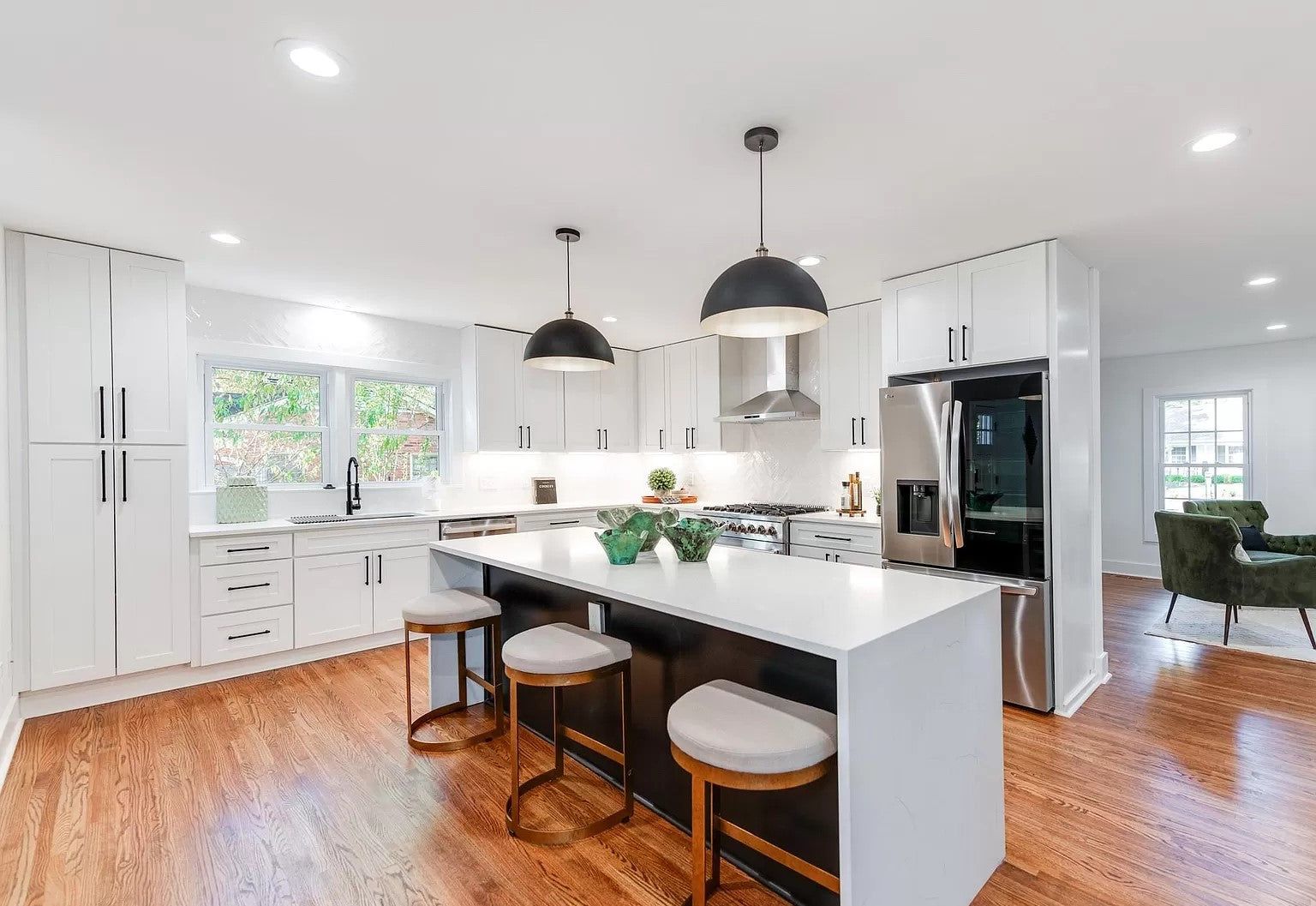 White shaker kitchen with a D8 Black Swan island, black pendants and hardwood floors
