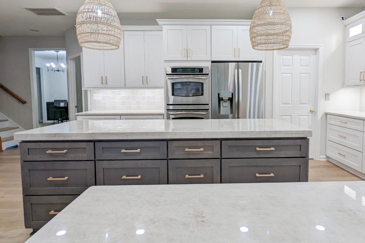 White shaker kitchen with a dark D5 Cyberspace island, quartz counters and rattan pendants