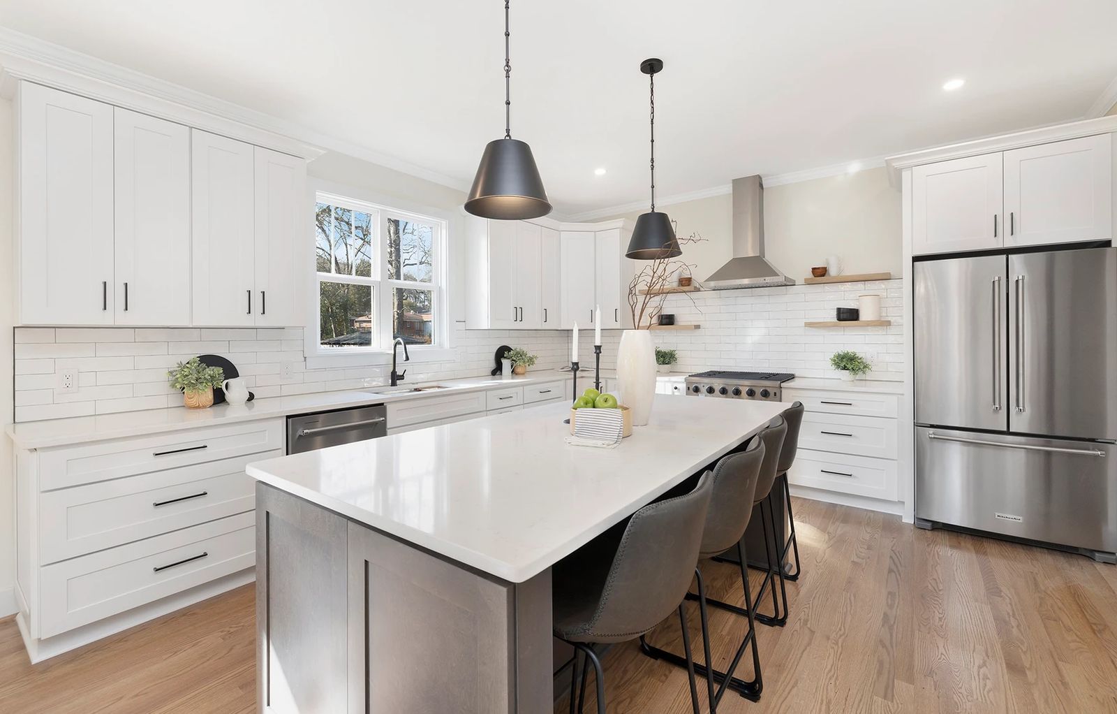 White shaker kitchen with a dark grey island, black pendant lights and stainless appliances