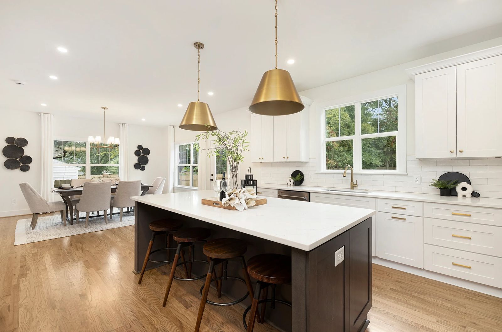 White shaker kitchen with a dark island and brass dome pendants
