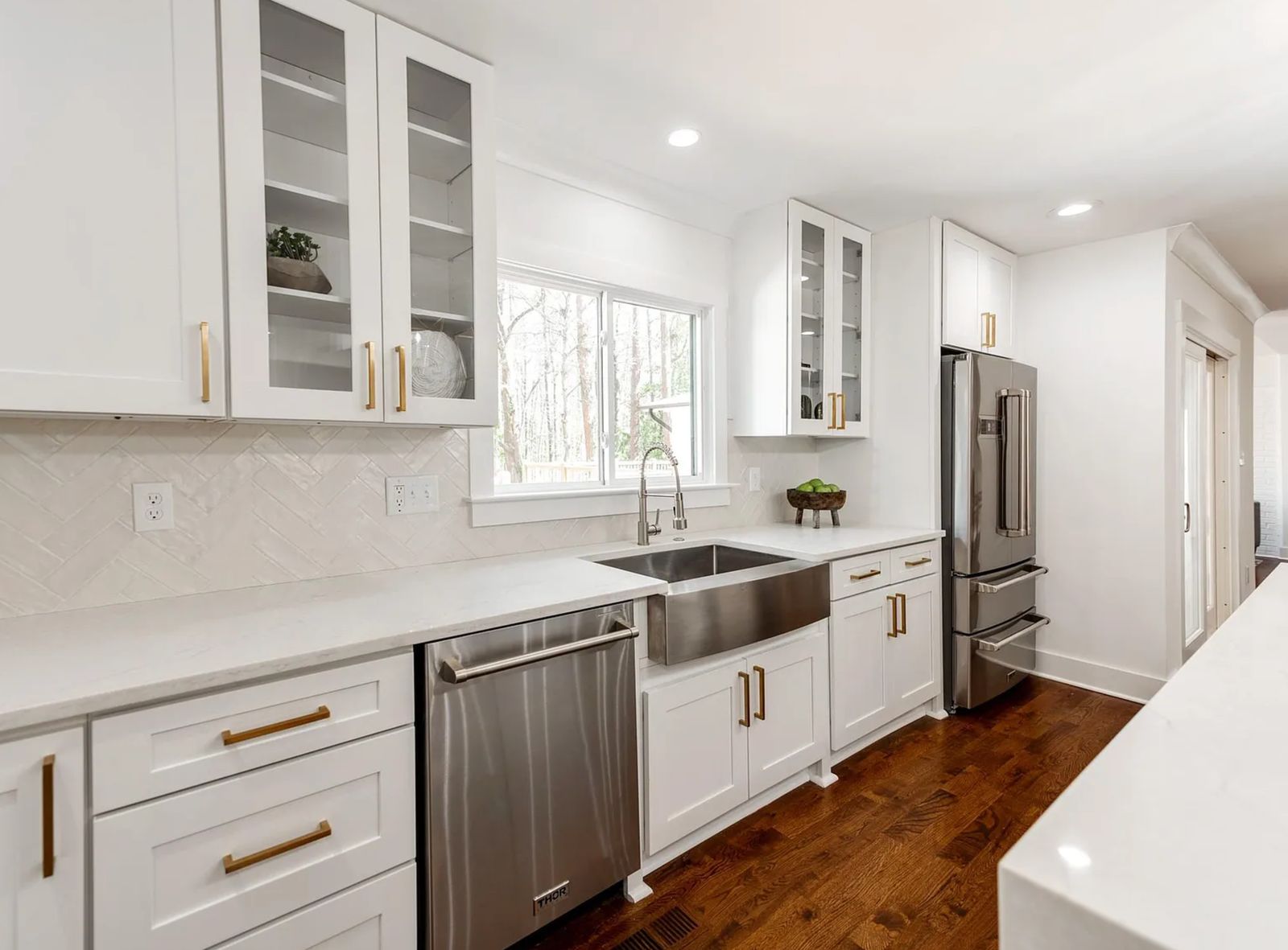 White shaker kitchen with glass uppers, stainless farmhouse sink and brass pulls