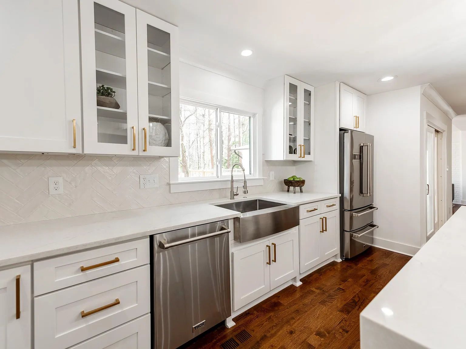 White shaker kitchen with glass uppers, stainless farmhouse sink and brass pulls