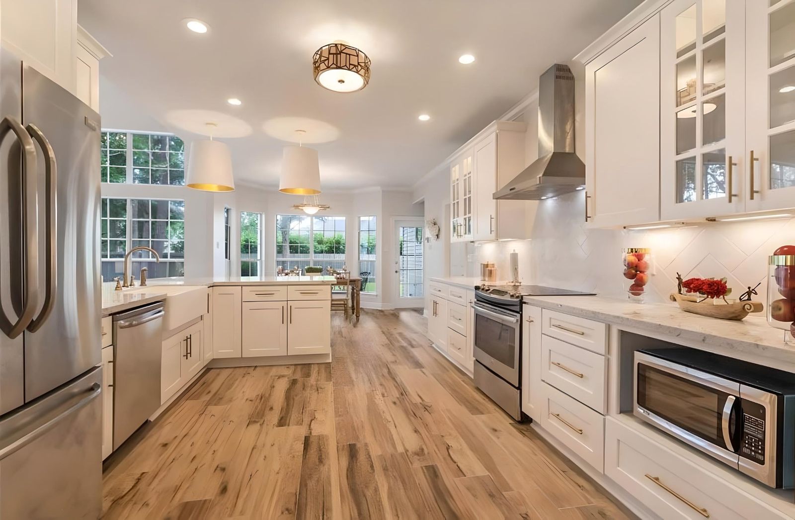 White shaker kitchen with glass uppers, stainless range hood and hardwood floors