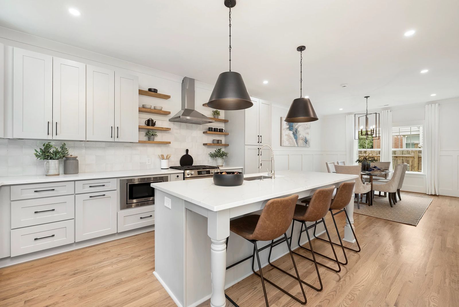 White shaker kitchen with a large island, black pendants and open dining area