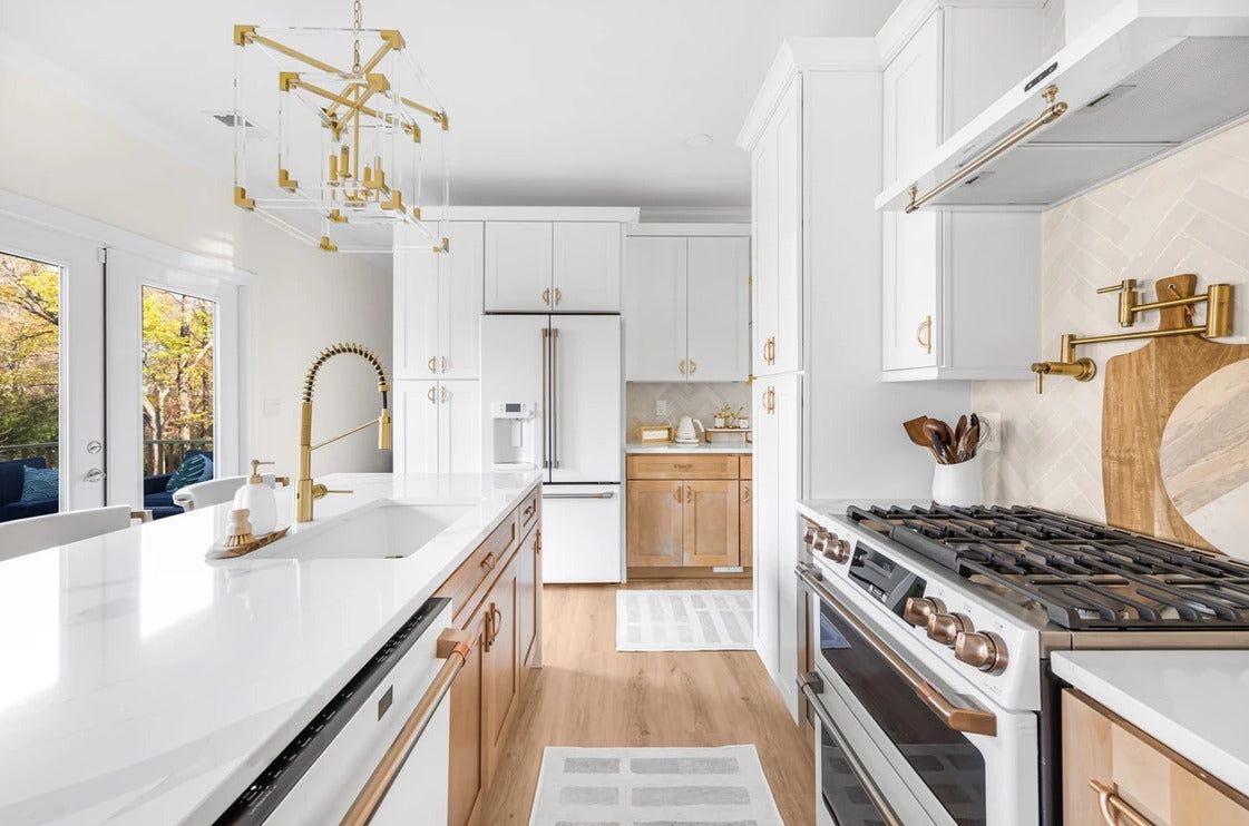 White shaker kitchen with natural oak accents, brass faucet and gold chandelier