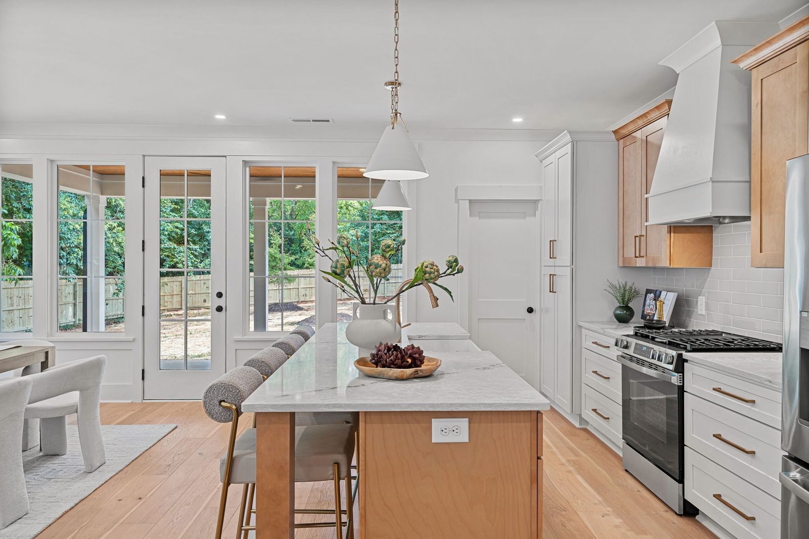 White shaker kitchen with a natural oak island, stainless range and French doors