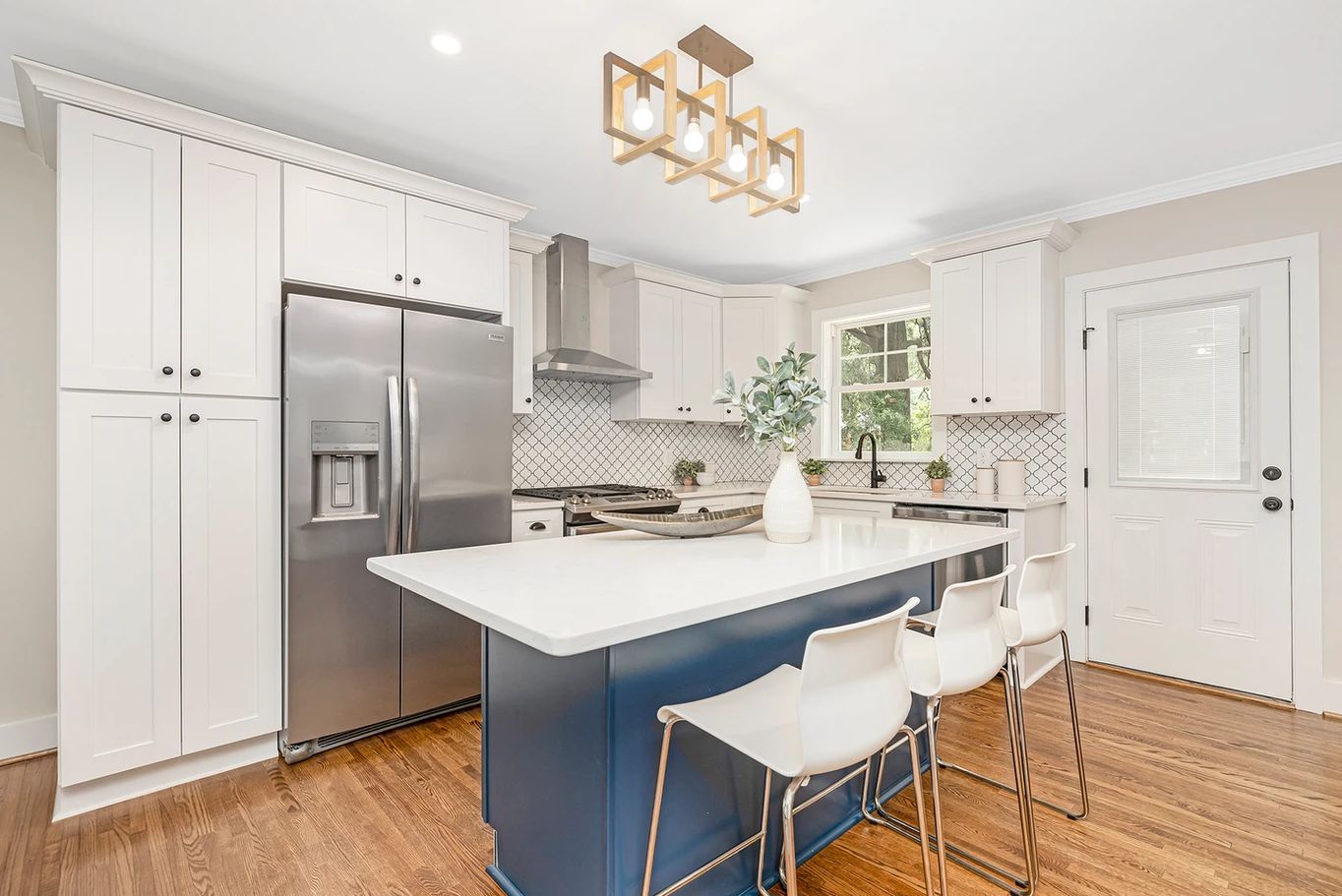White shaker kitchen with a navy island and stainless refrigerator