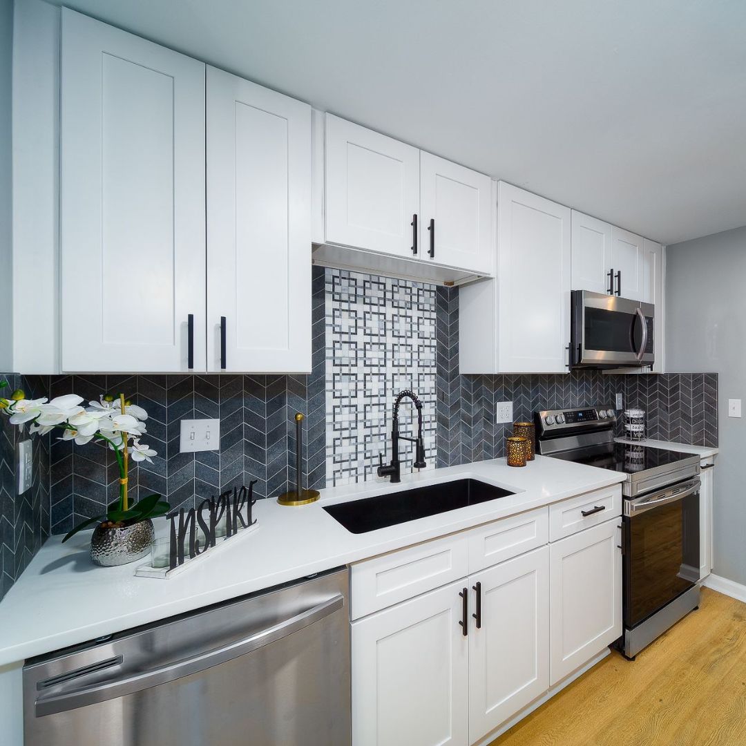 White shaker kitchen with navy patterned tile backsplash and black faucet