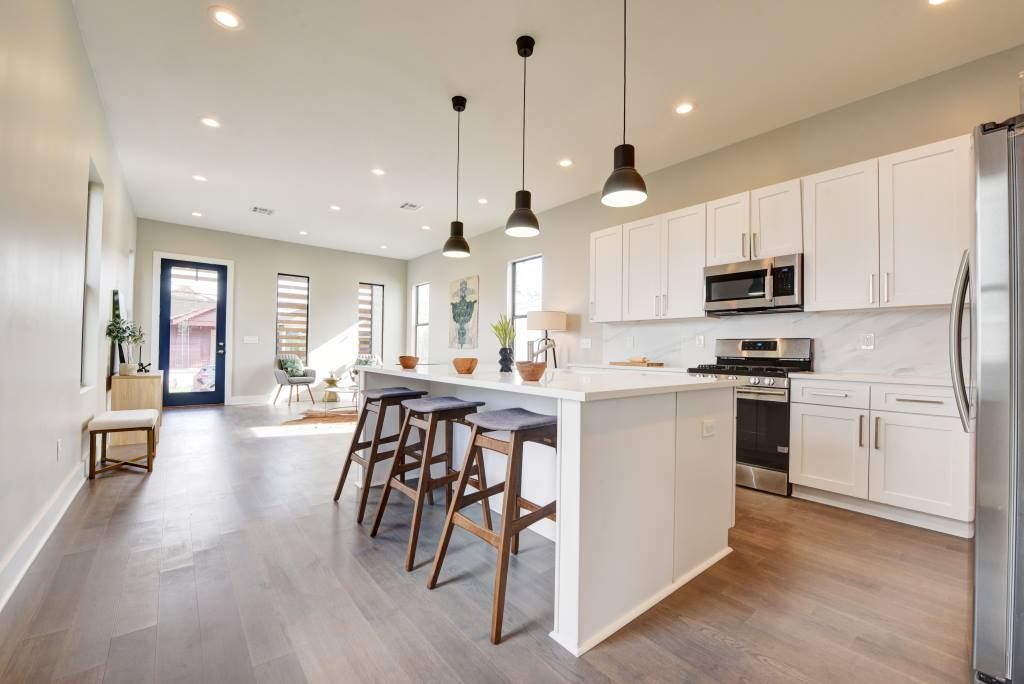 White shaker kitchen with quartz island, black pendants and open living space