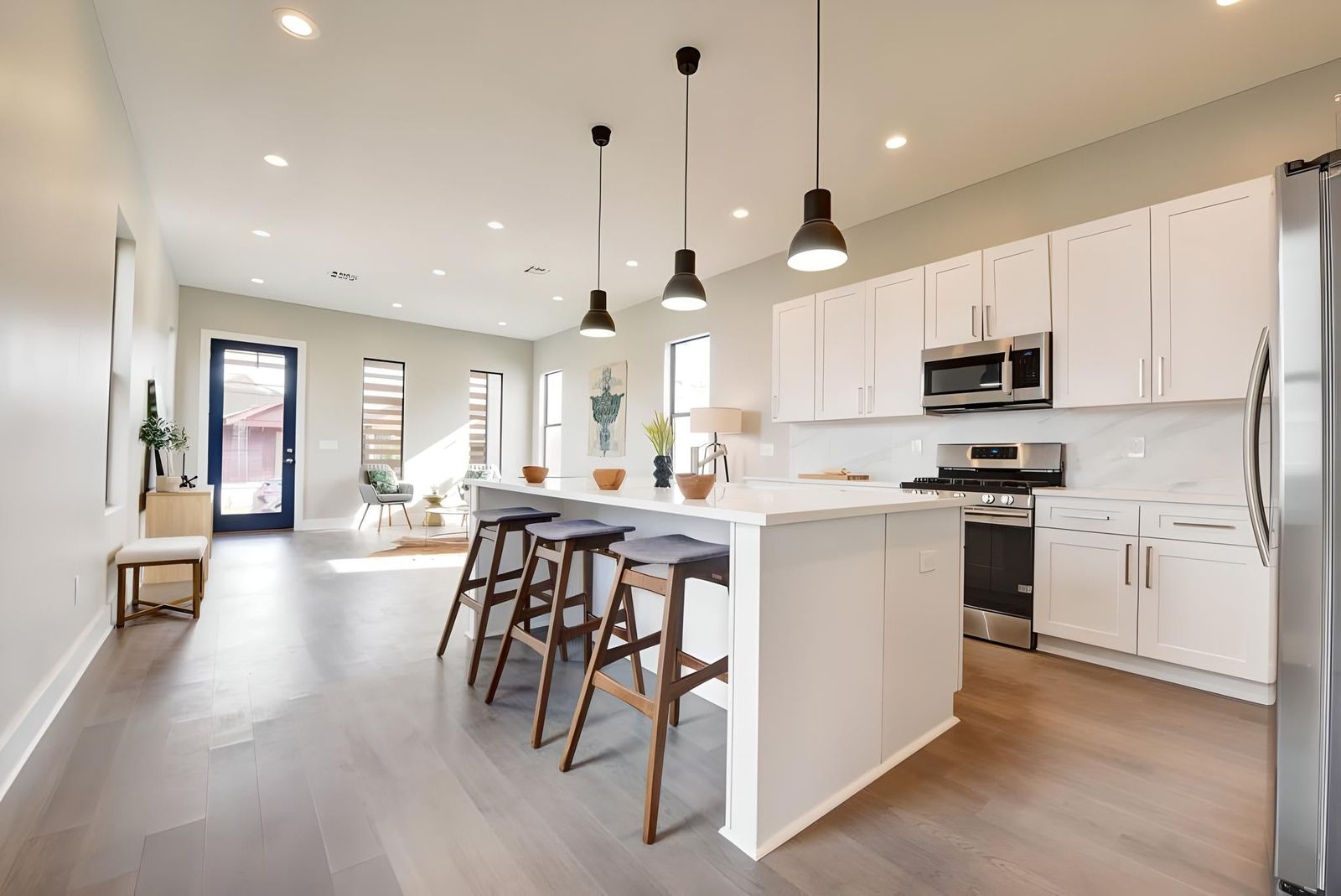 White shaker kitchen with quartz island, black pendants and stainless appliances