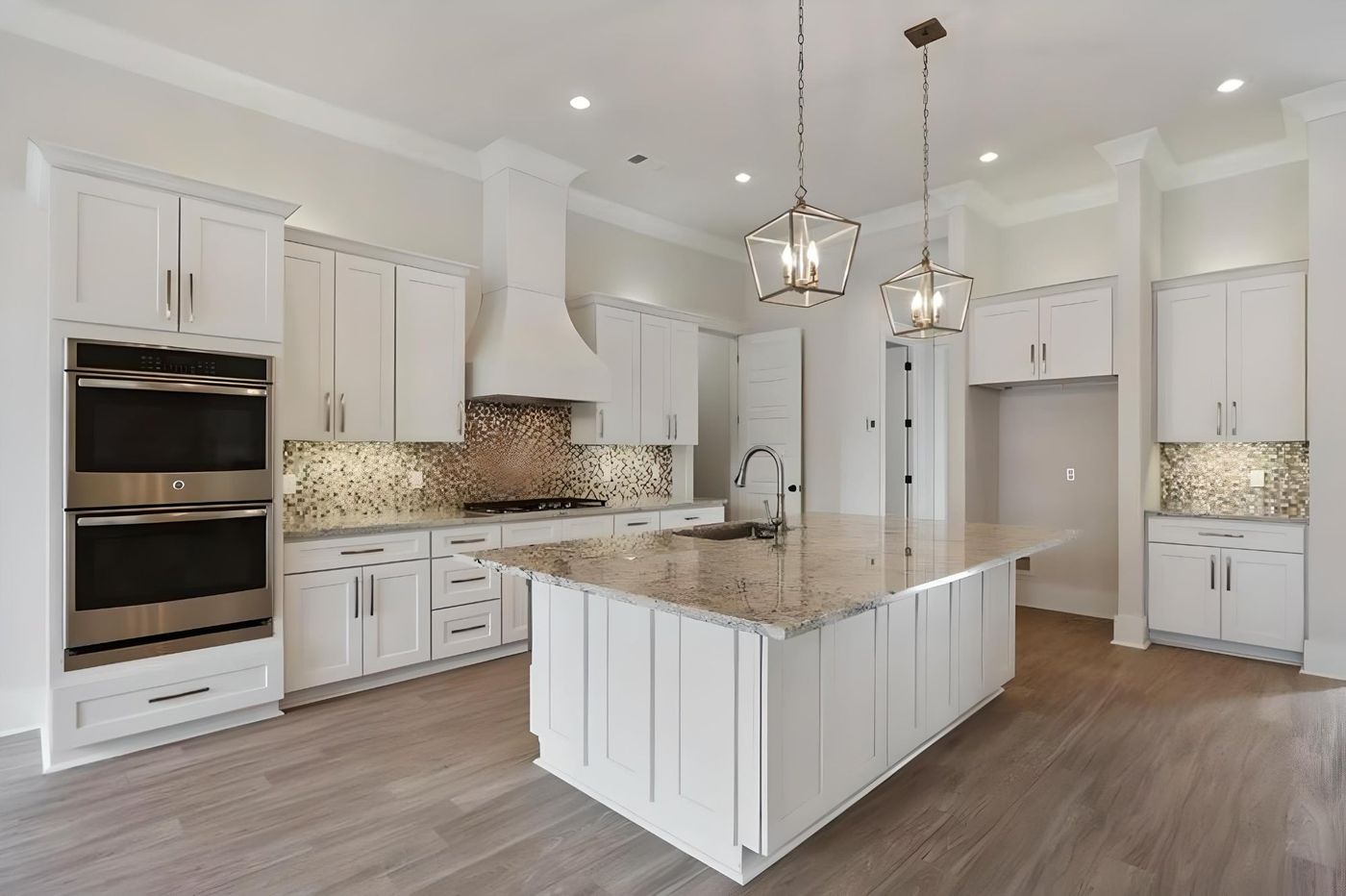 White shaker kitchen with quartz island, white range hood and lantern pendant