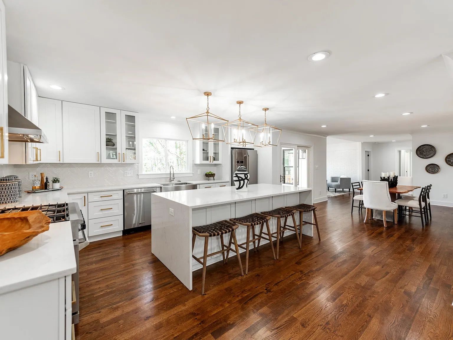 White shaker kitchen with quartz island, wood stools and open dining area